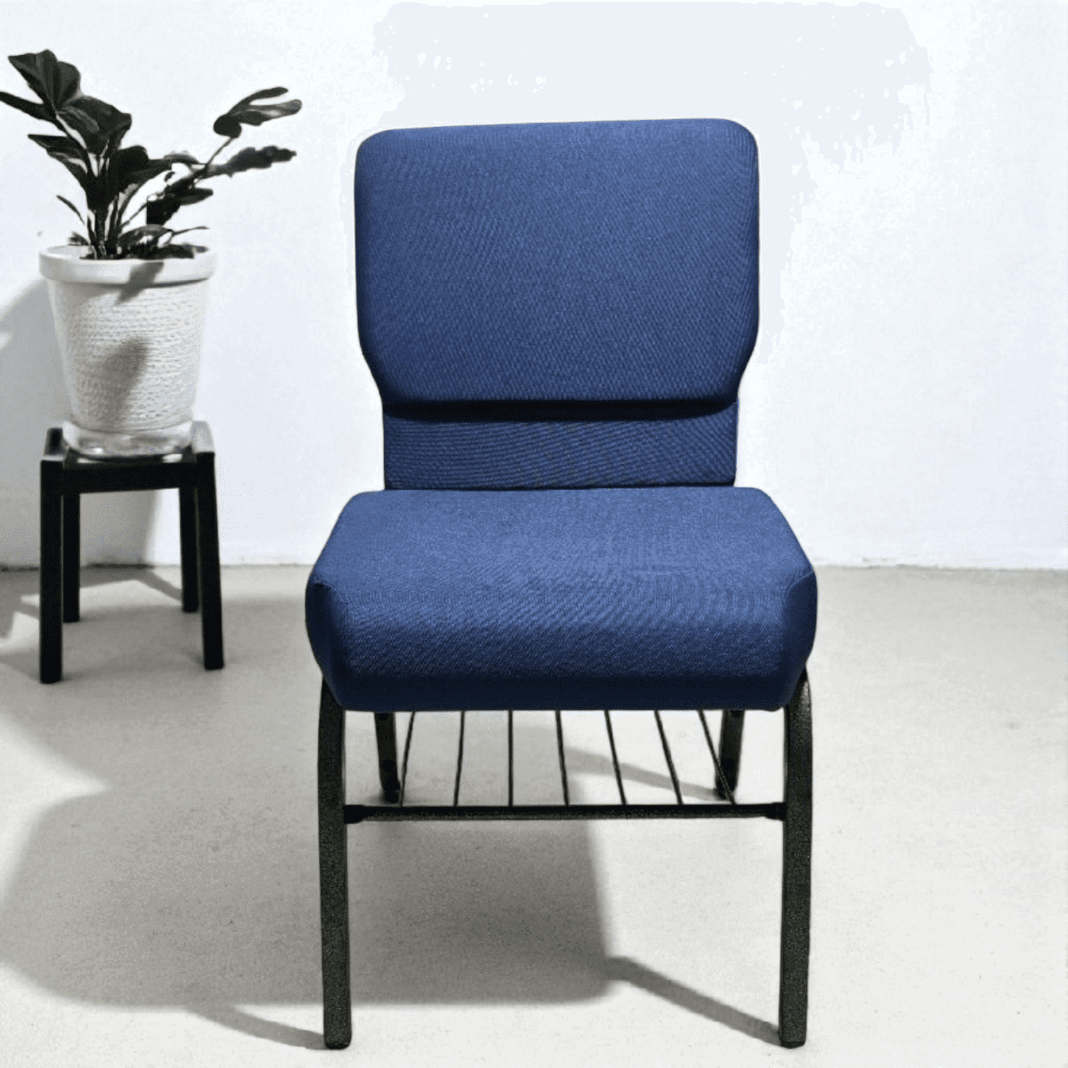 Modern blue chair with black metal frame and potted plant in background.