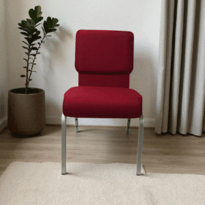 Red upholstered chair with metal legs beside a potted plant.
