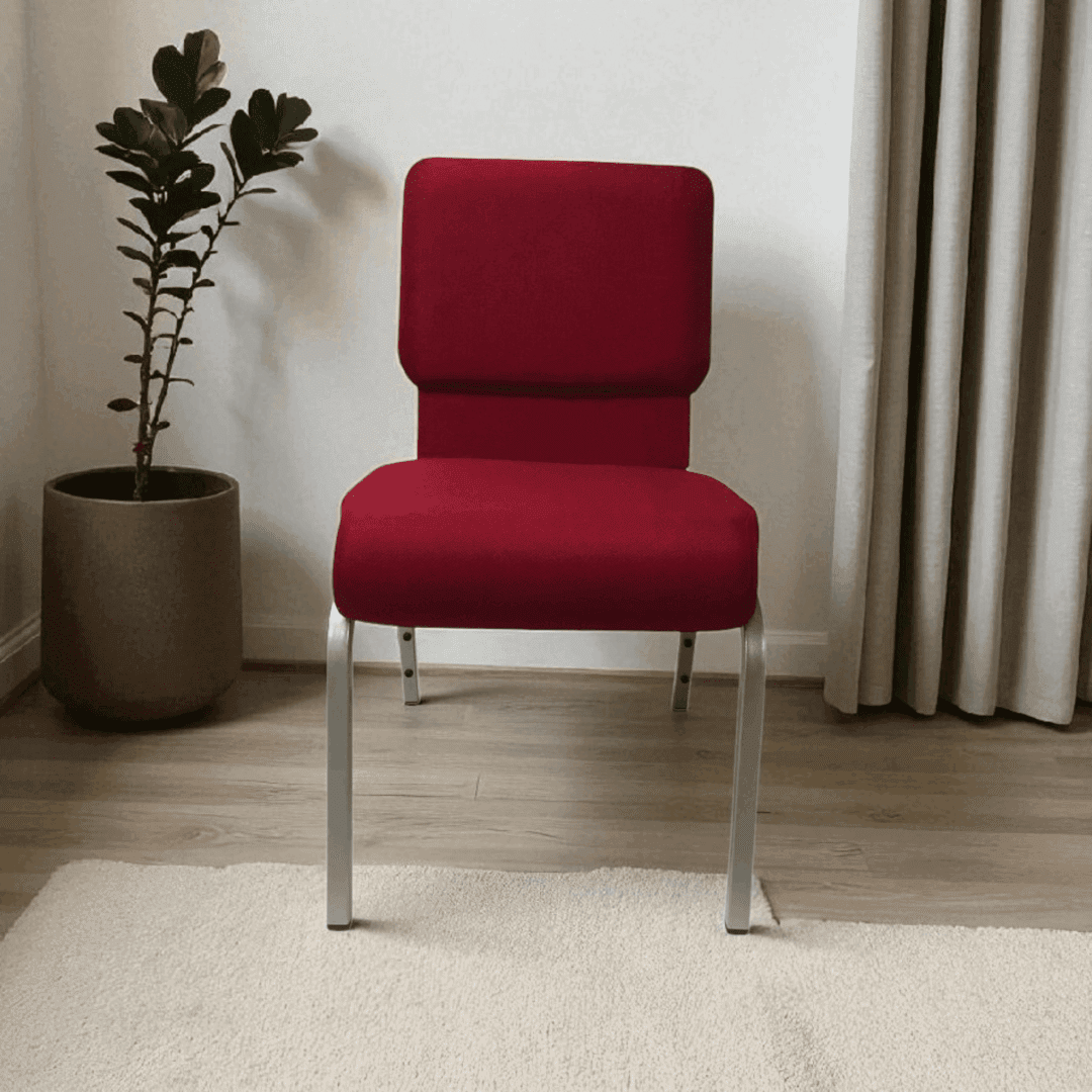 Red upholstered chair with metal legs beside a potted plant.