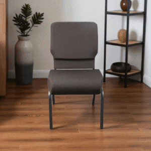 A modern gray chair with cushions on a wooden floor beside shelves and plants.