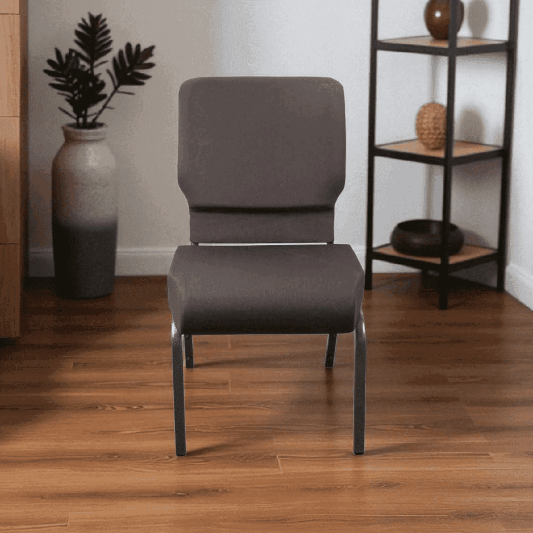 A modern gray chair with cushions on a wooden floor beside shelves and plants.