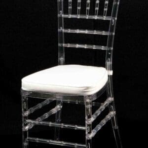 Transparent chair with a white cushion against a black background.