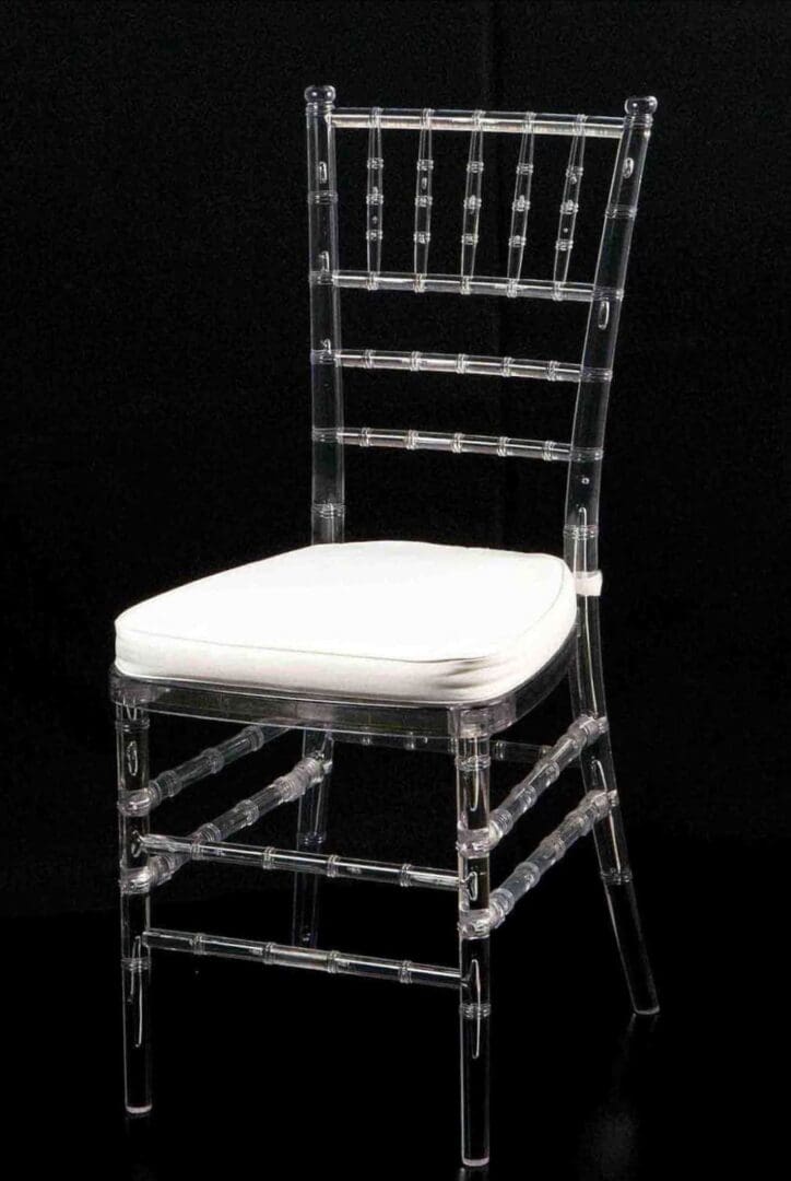 Transparent chair with a white cushion against a black background.
