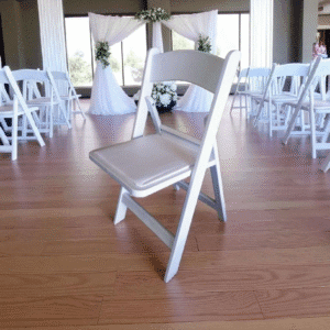 White folding chairs arranged in a decorated indoor event space.