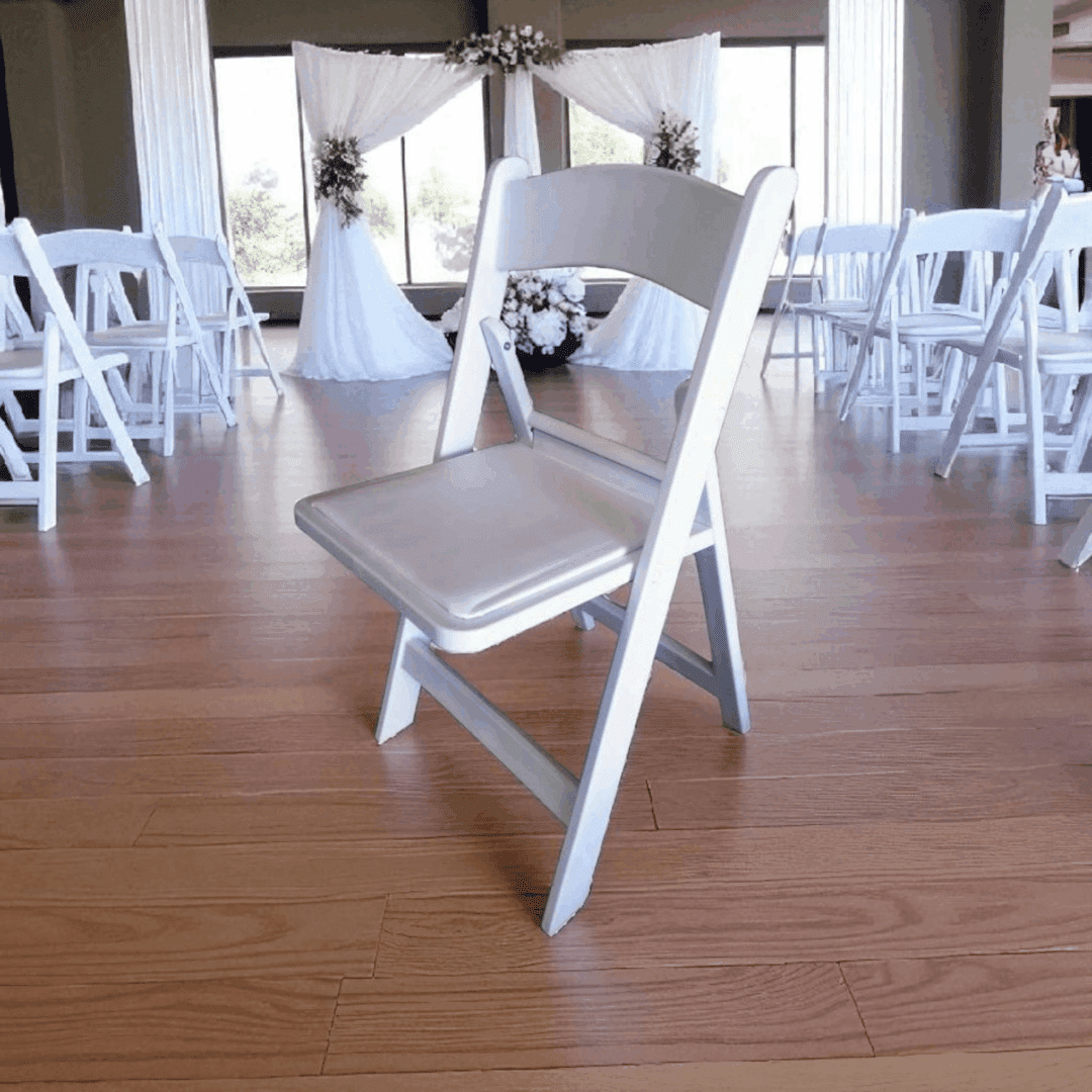 White folding chairs arranged in a decorated indoor event space.